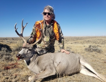 A hunter with his mule deer